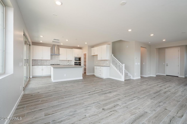 1571 E Tiffany Way, Gilbert, AZ 85298 - kitchen with wall chimney exhaust hood, open floor plan, light wood-style floors, backsplash, and recessed lighting