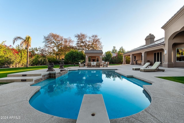 view of swimming pool featuring a diving board, a patio, and exterior fireplace