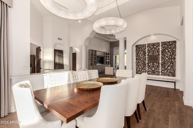 dining space with ornate columns, dark hardwood / wood-style flooring, and a towering ceiling