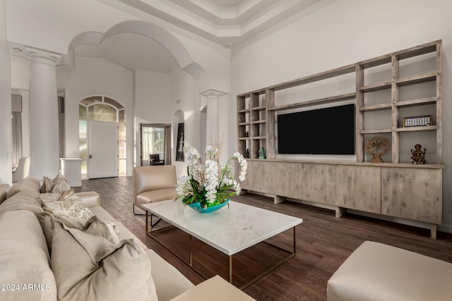 living room featuring decorative columns, dark hardwood / wood-style floors, and a high ceiling