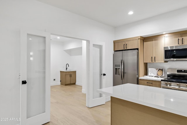 2774 E Valencia St, Gilbert, AZ 85296 - kitchen with stainless steel appliances, a sink, light wood-type flooring, light countertops, and tasteful backsplash