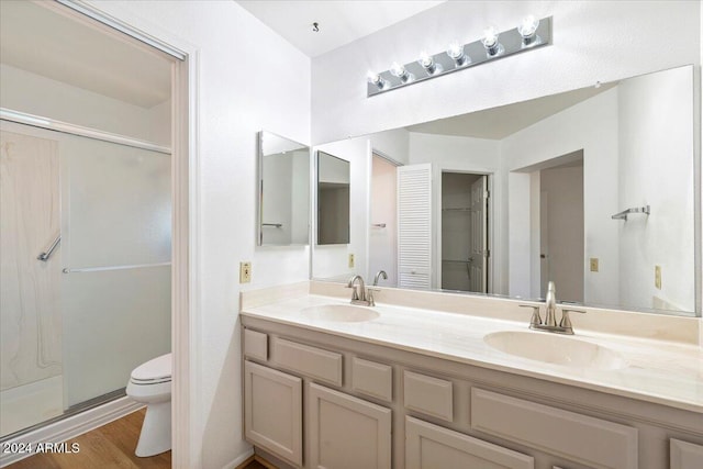 bathroom featuring vanity, wood-type flooring, toilet, and an enclosed shower