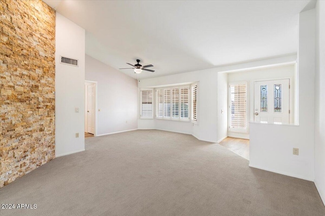 unfurnished living room with a wealth of natural light, vaulted ceiling, light carpet, and ceiling fan