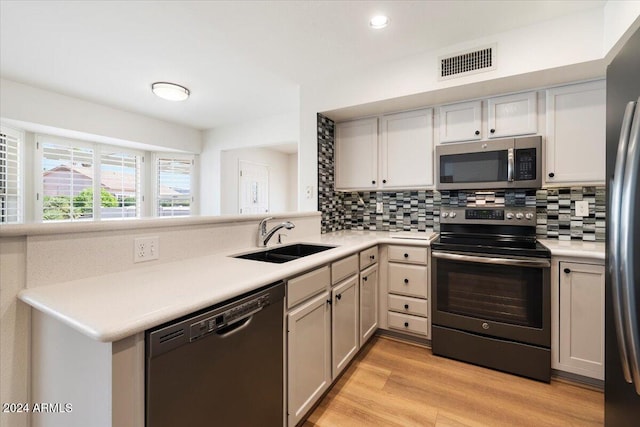 kitchen featuring light hardwood / wood-style flooring, stainless steel appliances, decorative backsplash, and sink