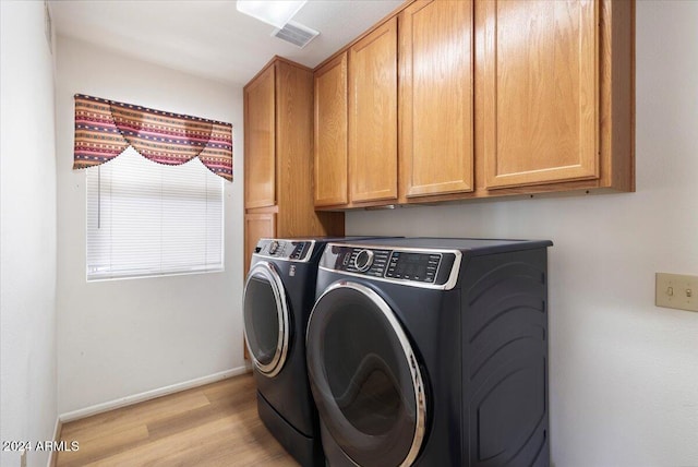 clothes washing area with washer and dryer, cabinets, and light wood-type flooring