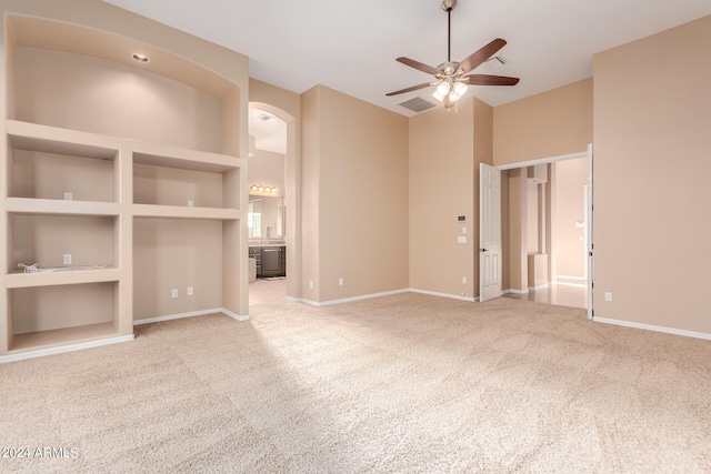 unfurnished living room with built in features, ceiling fan, and carpet floors