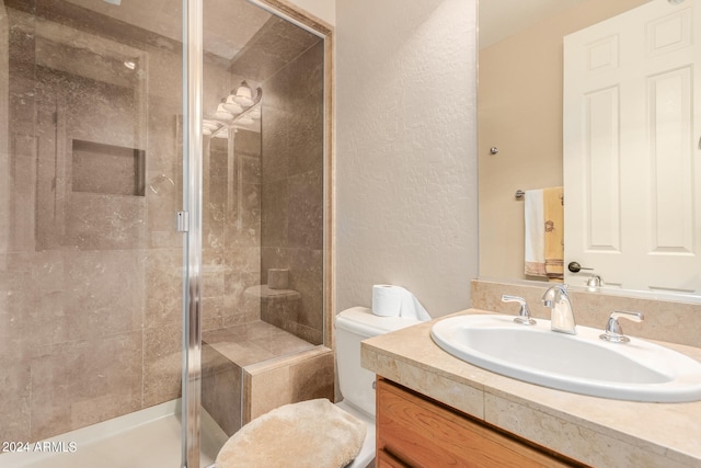 bathroom featuring a shower with shower door, toilet, and oversized vanity