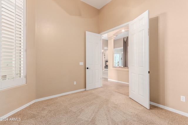 carpeted empty room with a healthy amount of sunlight and ornate columns