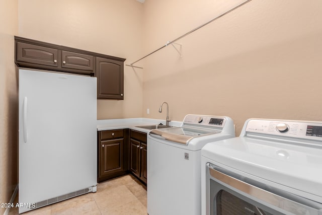 clothes washing area with cabinets, sink, separate washer and dryer, and light tile floors