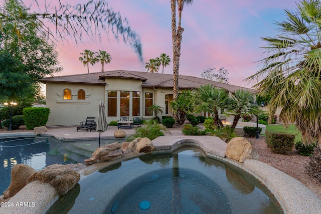 pool at dusk featuring a patio