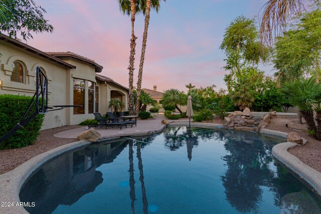 pool at dusk featuring a patio