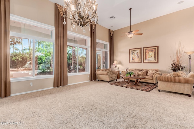 living room with a high ceiling, carpet flooring, and ceiling fan with notable chandelier