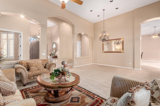 living room featuring ceiling fan with notable chandelier, decorative columns, a high ceiling, and carpet flooring