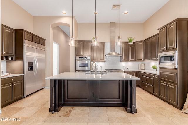 kitchen featuring built in appliances, pendant lighting, light tile flooring, wall chimney range hood, and sink