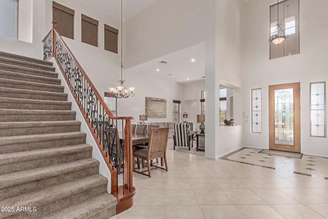 entryway with light tile patterned floors, baseboards, a high ceiling, and stairs
