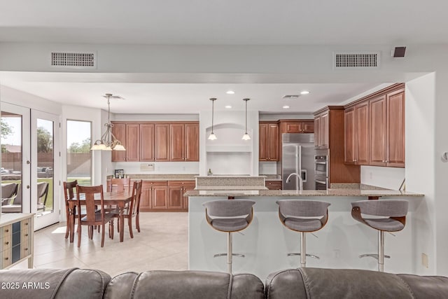 kitchen featuring a breakfast bar area, stainless steel appliances, visible vents, and a peninsula