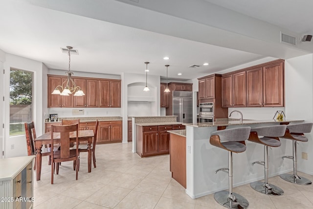 kitchen with light tile patterned flooring, stainless steel appliances, decorative light fixtures, a peninsula, and visible vents