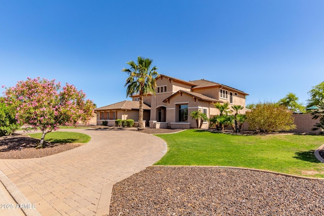 mediterranean / spanish house with fence, curved driveway, a front lawn, and stucco siding