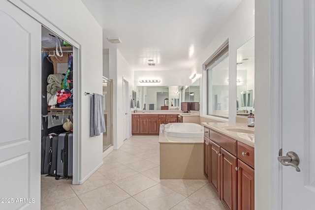 full bath with a shower stall, tile patterned floors, two vanities, and a walk in closet