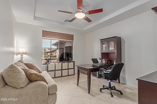 home office with a raised ceiling, a ceiling fan, light tile patterned flooring, and visible vents