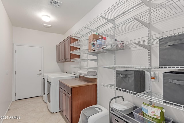 clothes washing area featuring cabinet space, light tile patterned flooring, washing machine and clothes dryer, baseboards, and visible vents