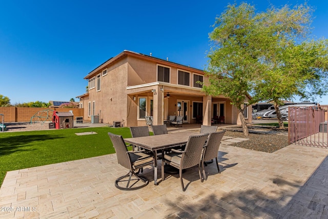 back of house featuring a lawn, a ceiling fan, a patio, and stucco siding