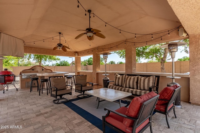 view of patio featuring outdoor dry bar, ceiling fan, area for grilling, outdoor lounge area, and a fenced backyard