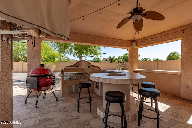 view of patio with a fenced backyard, exterior kitchen, outdoor wet bar, and grilling area