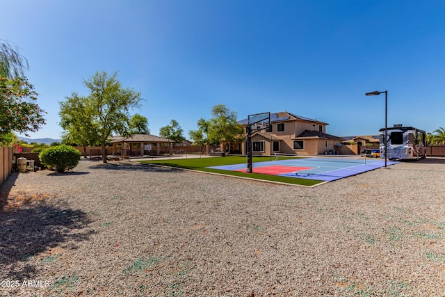 exterior space featuring a lawn, fence, and basketball hoop