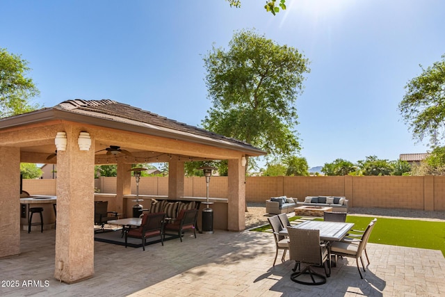 view of patio with a gazebo, a fenced backyard, an outdoor living space with a fire pit, and outdoor dining area