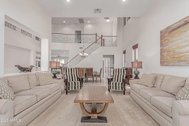 carpeted living room with visible vents, a towering ceiling, and stairway