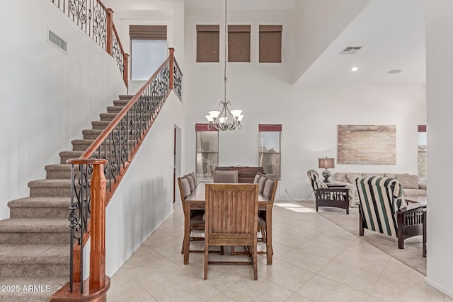 dining room featuring stairway, a towering ceiling, a notable chandelier, and visible vents