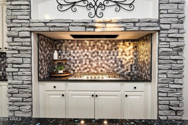 bar with tasteful backsplash, white cabinets, extractor fan, and stainless steel gas cooktop