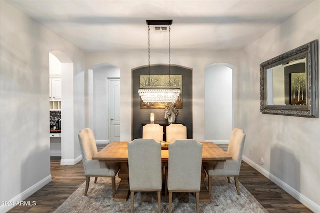 dining space with dark wood-type flooring and an inviting chandelier