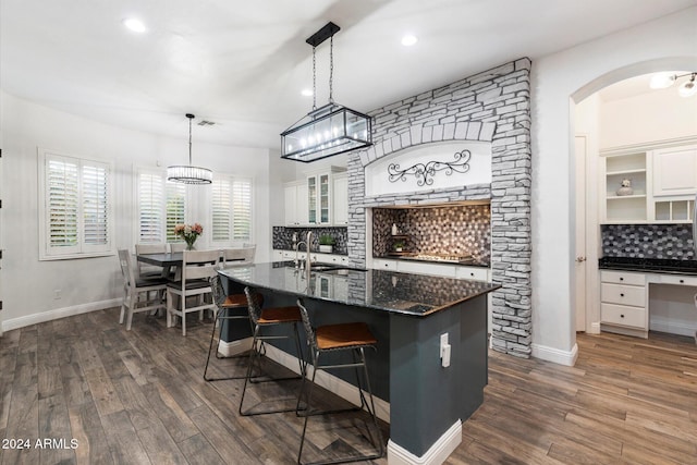 kitchen with white cabinetry, pendant lighting, dark wood-type flooring, and a center island with sink