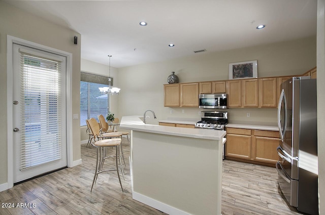 14430 N Agave Dr, Fountain Hills, AZ 85268 - kitchen with pendant lighting, an inviting chandelier, a center island with sink, light wood-type flooring, and stainless steel appliances