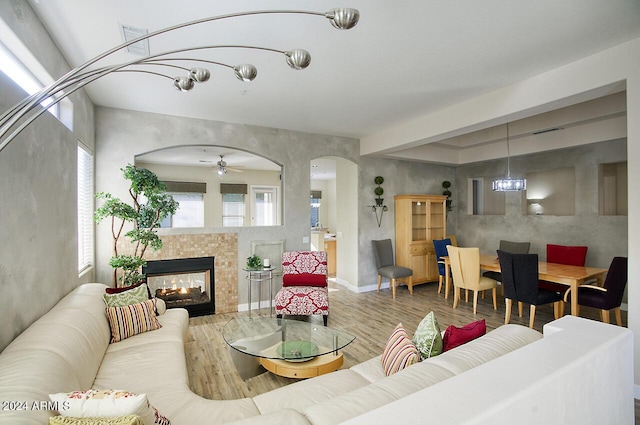 living room with hardwood / wood-style flooring, ceiling fan with notable chandelier, and a tile fireplace