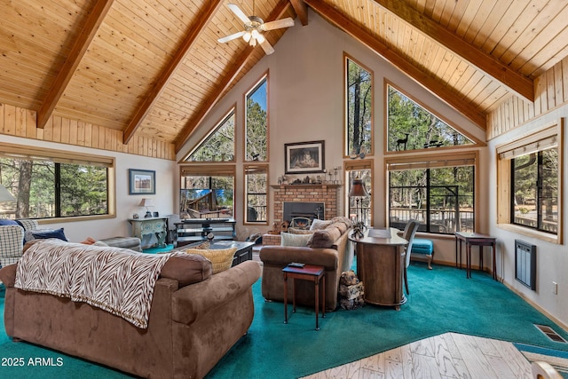 carpeted living room with beamed ceiling, high vaulted ceiling, a brick fireplace, and a healthy amount of sunlight