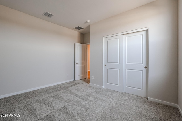 unfurnished bedroom featuring light carpet and a closet