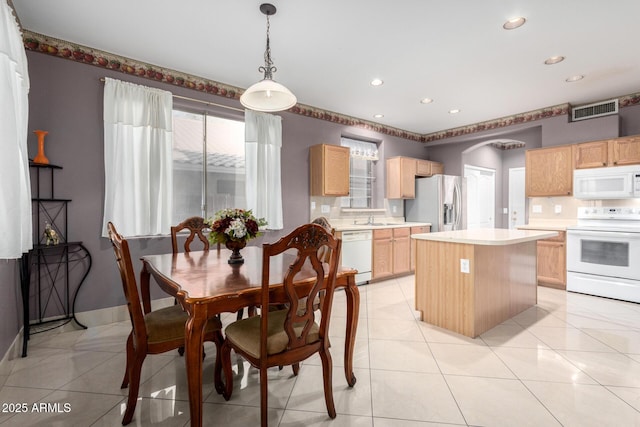 kitchen featuring sink, a center island, hanging light fixtures, light tile patterned floors, and white appliances