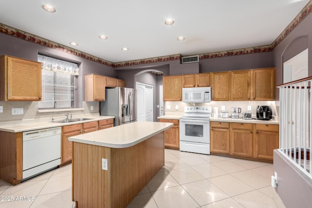 kitchen with sink, white appliances, a center island, and light tile patterned floors