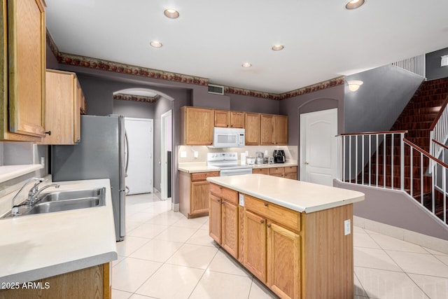 kitchen with sink, white appliances, light tile patterned floors, and a kitchen island