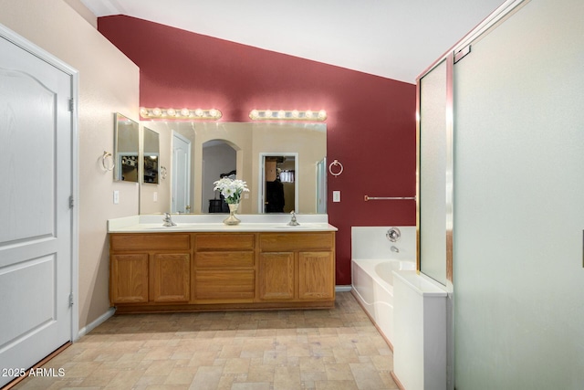 bathroom featuring vanity, a tub to relax in, and vaulted ceiling