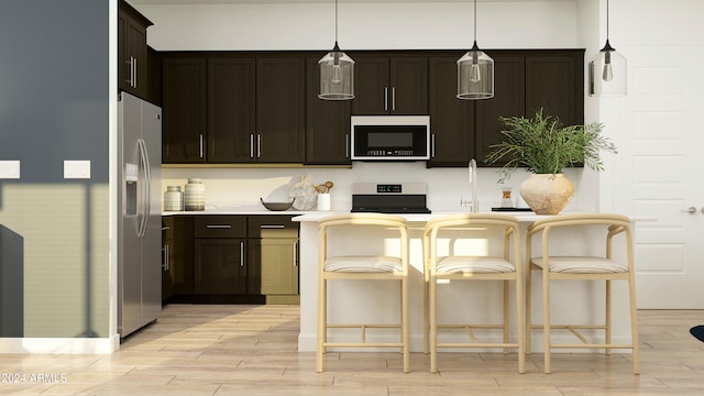 kitchen featuring a breakfast bar area, hanging light fixtures, light hardwood / wood-style floors, stainless steel appliances, and dark brown cabinets