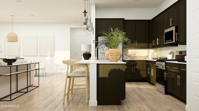 kitchen featuring appliances with stainless steel finishes, a kitchen breakfast bar, a kitchen island, decorative light fixtures, and light wood-type flooring