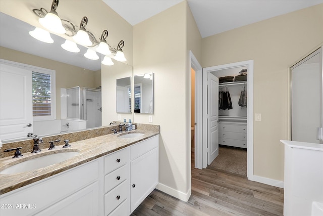 bathroom with hardwood / wood-style floors, a shower with shower door, and vanity