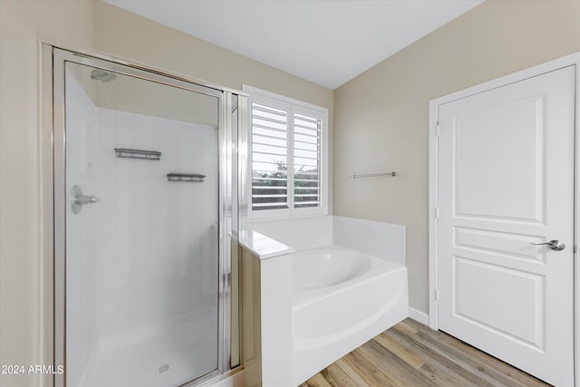 bathroom with wood-type flooring and shower with separate bathtub