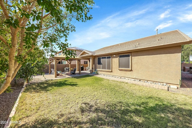 rear view of property with a gazebo, a patio, and a lawn