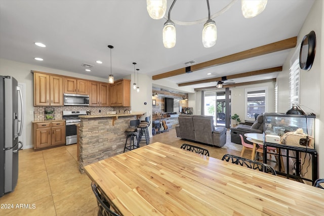 dining space with light tile patterned flooring, ceiling fan, and beam ceiling