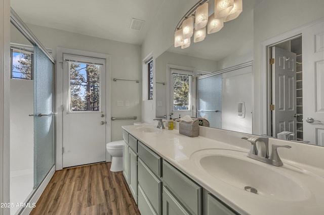 full bathroom with a sink, visible vents, wood finished floors, and a stall shower